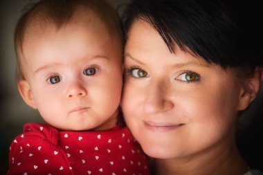 9. aylık kızıyla genç bir anne portreye sarılıyor. Ailenin doğal ışık çekimi.