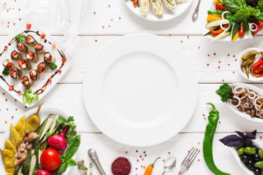 White ceramic plate surrounded by snacks, void