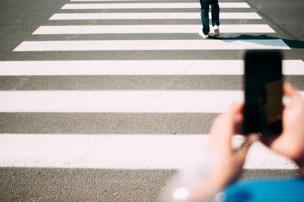 Pedestrian zebra closeup, smartphone on foreground