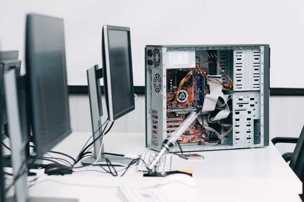 Unidade de computador desmontada na mesa com monitores — Fotografia de Stock