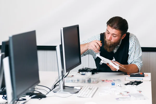 Maître barbu démontage drone dans le bureau — Photo