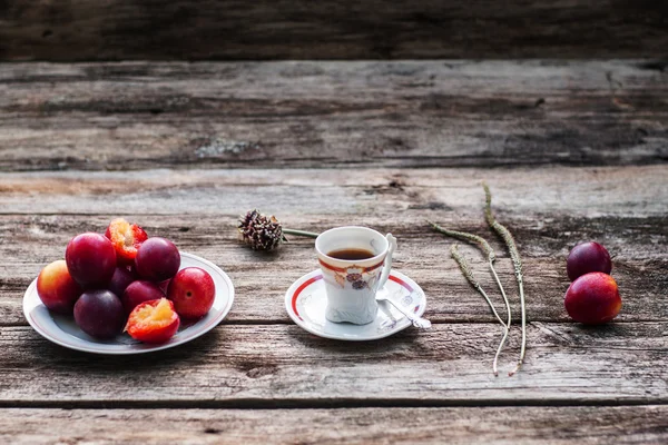 Tasse Kaffee und frische Pflaumen auf Holz, freier Raum — Stockfoto