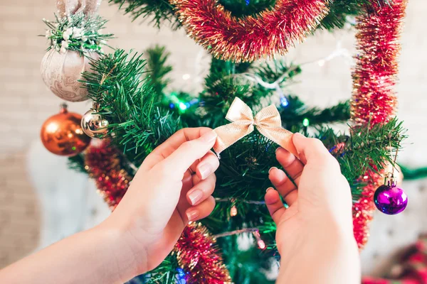 Hand hängt süße goldene Schleife am Weihnachtsbaum — Stockfoto