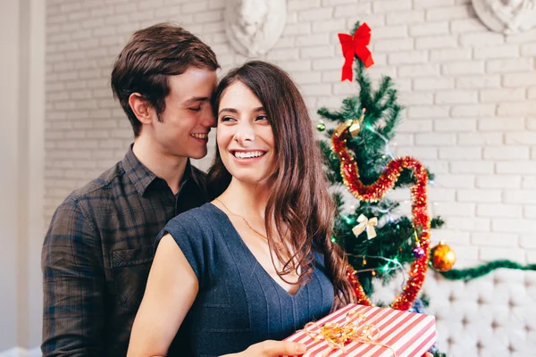 Glimlachende man hugs zijn vriendin met heden — Stockfoto