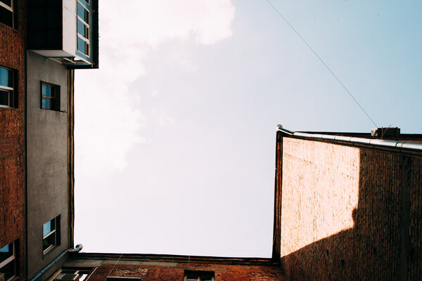 View from below on old brick house with blue sky, copy space. Frame of building with free space of heaven with white clouds.