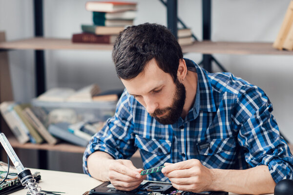 Bearded engineer examing micro circuit