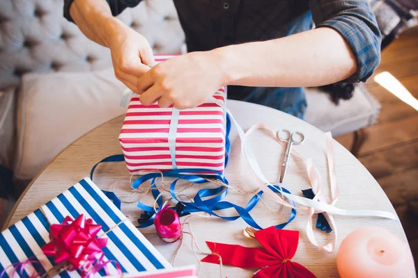 Man decorating present box with ribbon