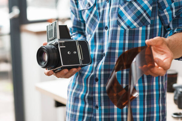 Фотограф, стоящий с ретро камерой и пленкой
