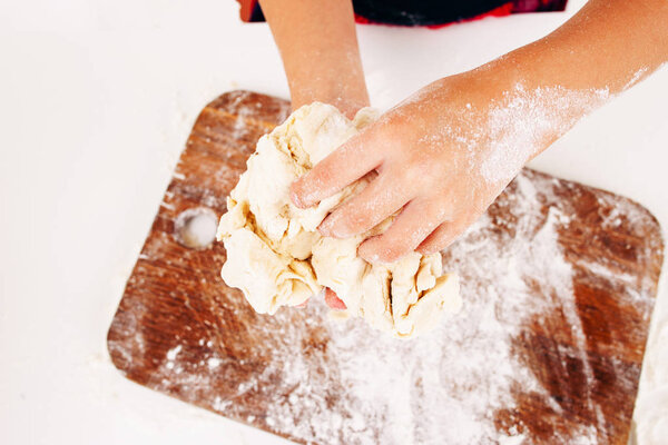 Kid hands with dough close-up, top view