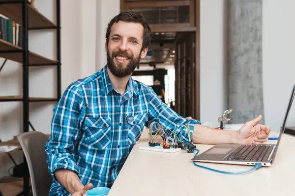 Programador feliz sorrindo para a câmera perto do laptop — Fotografia de Stock