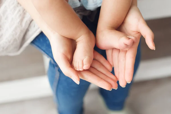 Lilla nyfödda baby ben på kvinnliga händer, närbild — Stockfoto