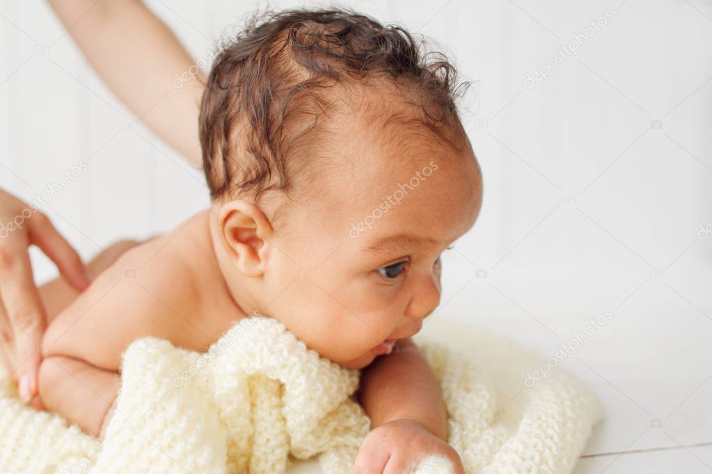 Portrait of baby lying on blanket holding head up