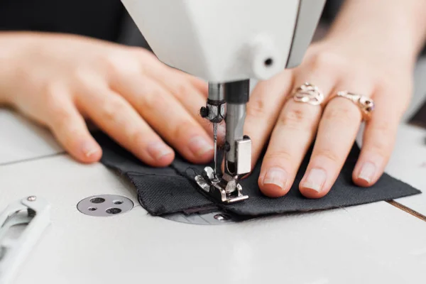 Mãos de mulher com tecido em máquina de costura — Fotografia de Stock
