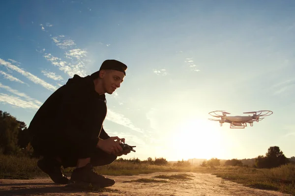 Jovem correndo drone ao ar livre ao pôr do sol — Fotografia de Stock