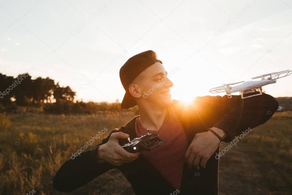 Smiling guy with rc drone on his shoulder, sunset