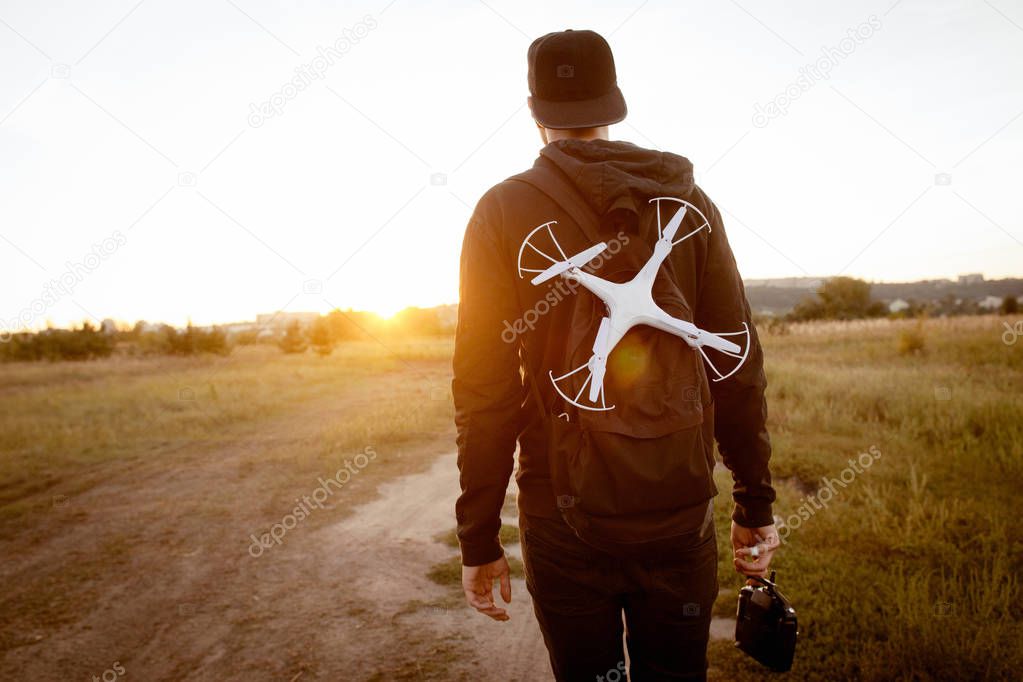 Young man with drone go to sunset, free space