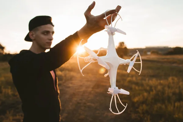 Man holding drone for propeller, sunset flare