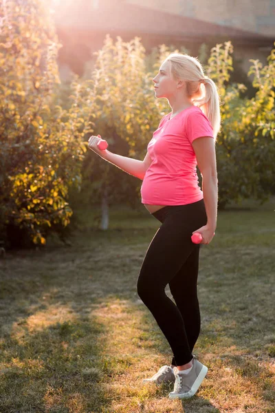 Oldalnézetből a terhes nő a súlyzó — Stock Fotó