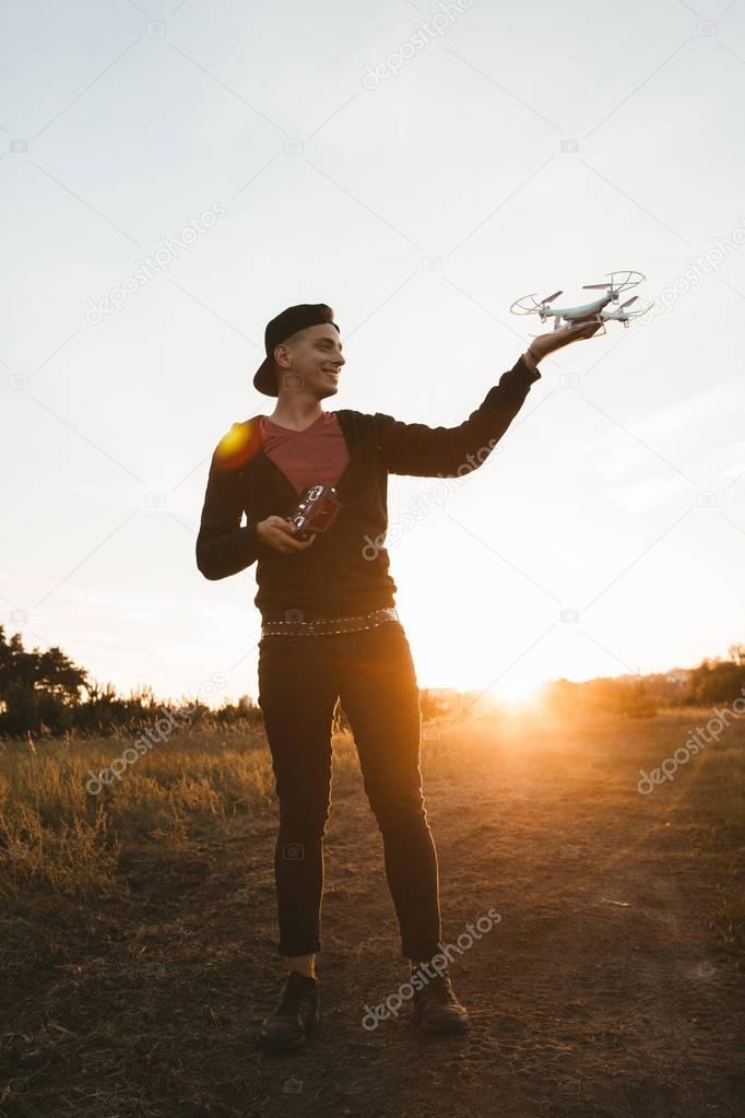 Full-length photo of man with drone, sunset flare