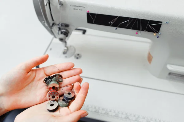 Female hands holding bobbins near sewing machine — Stock Photo, Image