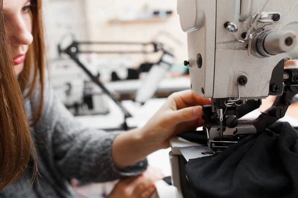 Vrouwelijke kleermaker vaststelling vast weefsel bij apparatuur — Stockfoto