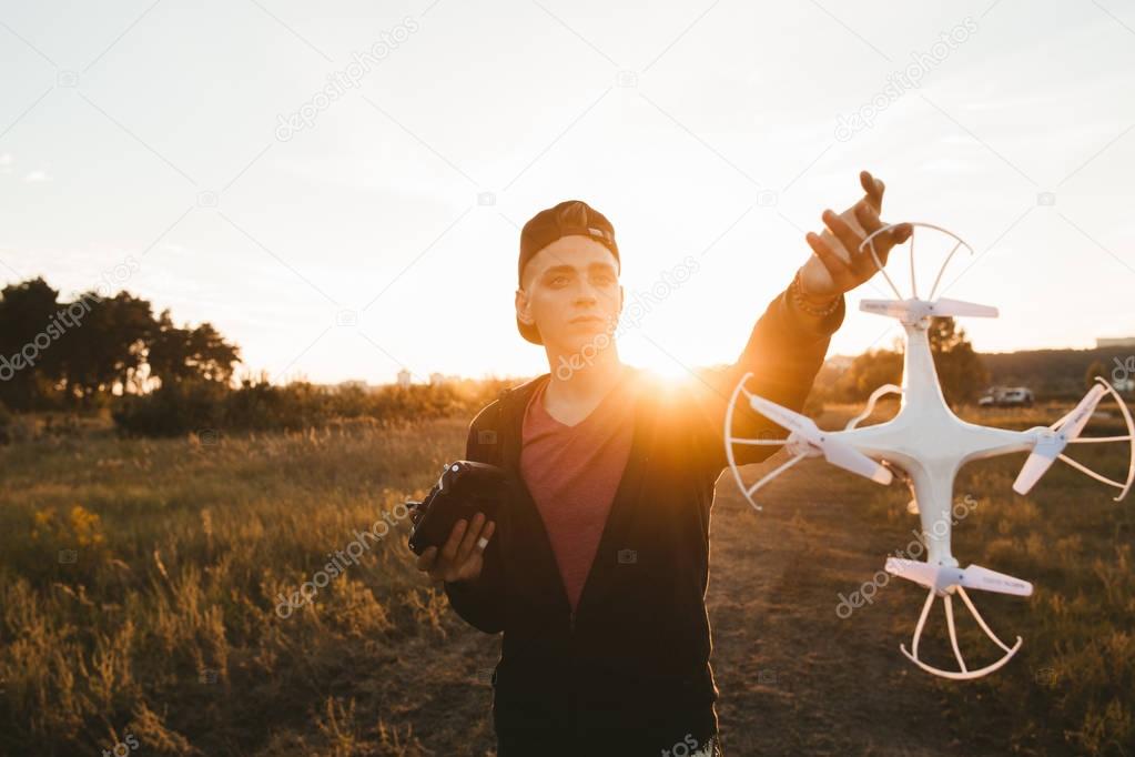 Young man showing drone to camera, sunset flare