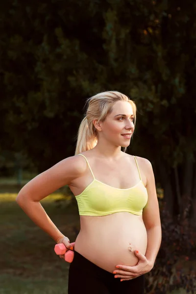 Smiling pregnant woman caress her belly at nature — Stock Photo, Image