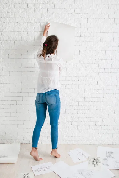 Zadní žena visí prázdný papír na zeď maketa — Stock fotografie