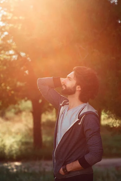 Perfil del hombre disfrutando de la luz solar en el bosque — Foto de Stock