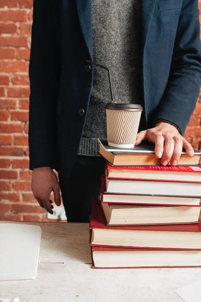Невпізнаваний чоловік стоїть на книгах і каві — стокове фото