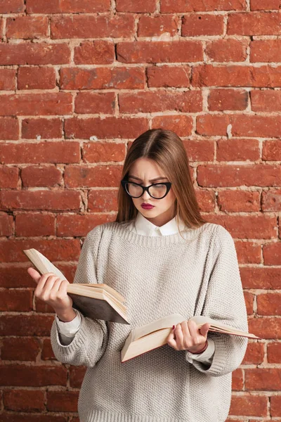 Chica muy inteligente leyendo dos libros al mismo tiempo —  Fotos de Stock
