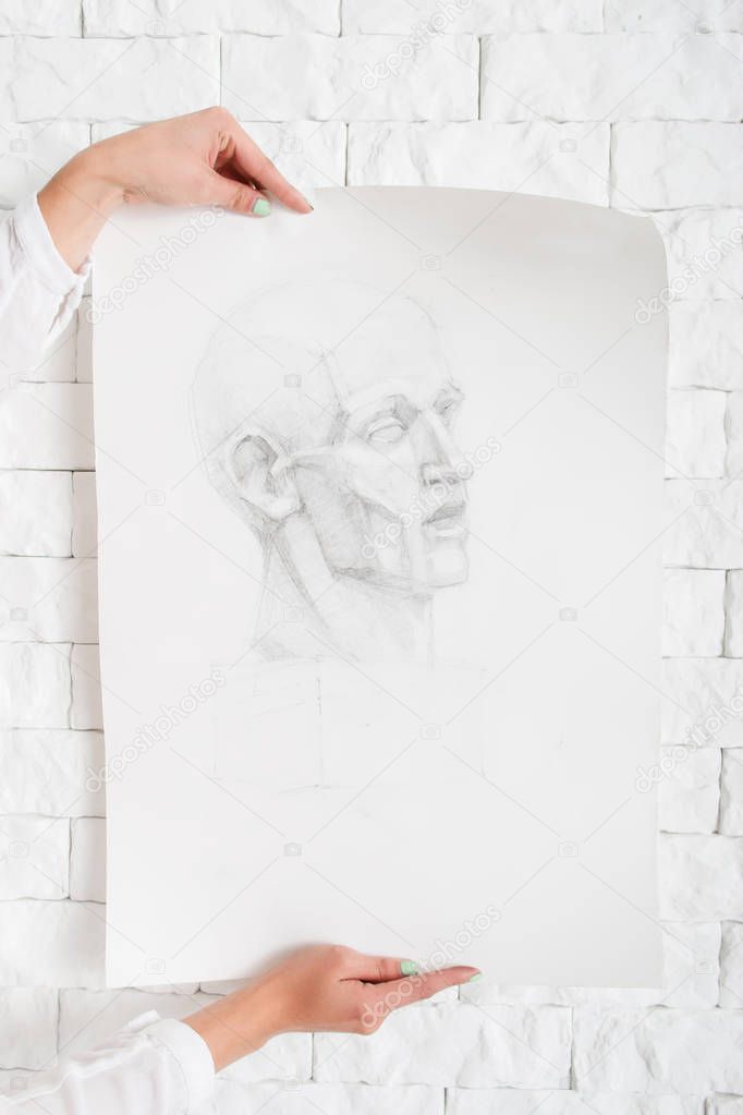 Pencil portrait in artist hands against wall