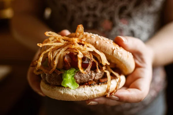 Välsmakande hamburgare med lök i kvinnliga händer — Stockfoto