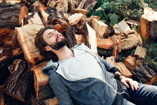 Lenhador cansado dormindo em pilha de madeira — Fotografia de Stock