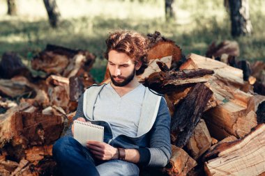 Ciddi adam not defterinde odun yığını üzerinde yazma