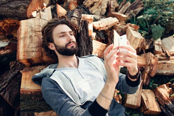 Man using smartphone on pile of wood