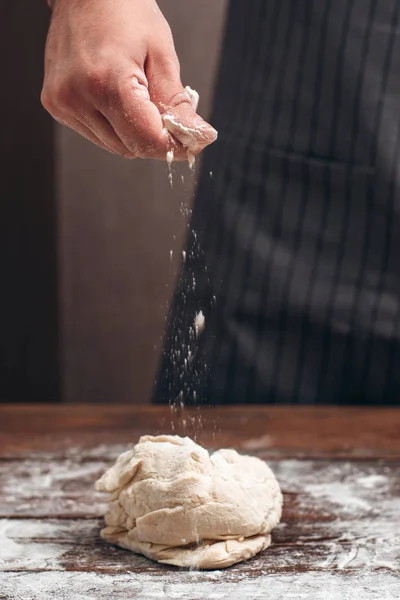 Пекарь посыпать муку над сырым тестом — стоковое фото