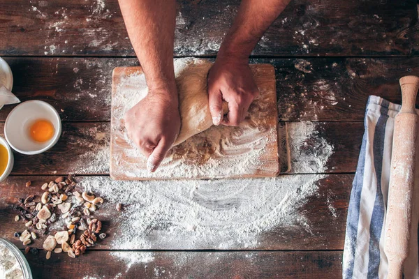 Hands kneading raw dough on table flat lay