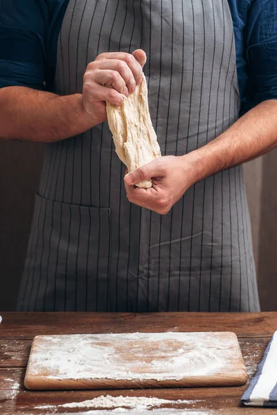 Unrecognizable baker stretching dough at kitchen — Stock Photo, Image