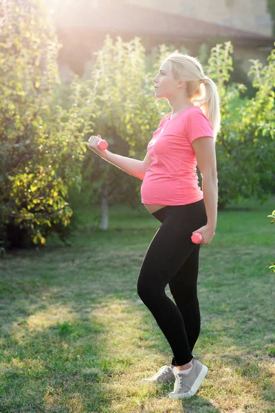 Oldalnézetből a terhes nő a súlyzó — Stock Fotó