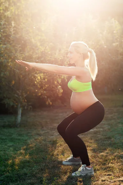 Terhes nő guggoló kültéri, napkelte fény — Stock Fotó