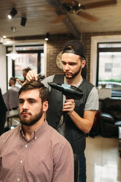 Стиліст робить сучасне зачіску для молодого чоловіка — стокове фото