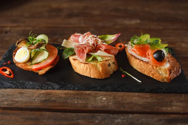 Pequenos canapés que colocam na bandeja preta — Fotografia de Stock