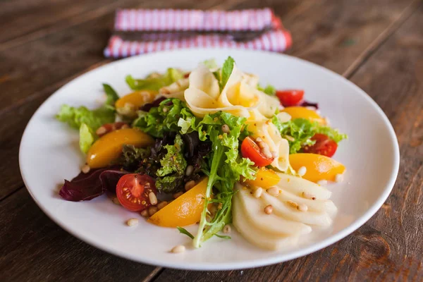 Grön sallad med ost och frukt på tallrik — Stockfoto