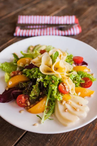 Зеленый салат с сыром и фруктами на тарелке — стоковое фото
