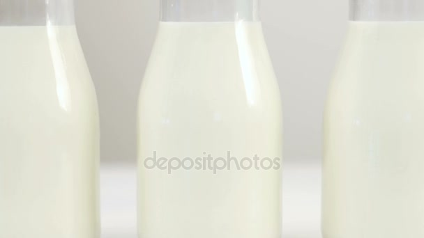 Primer plano tres botellas de leche gota — Vídeos de Stock
