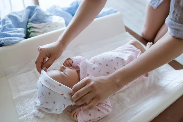 Mutter kleidet ihr Neugeborenes sorgfältig ein — Stockfoto