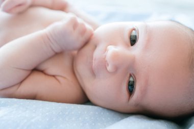 Yeni doğan bebek yatakta yatarken gülümseyen
