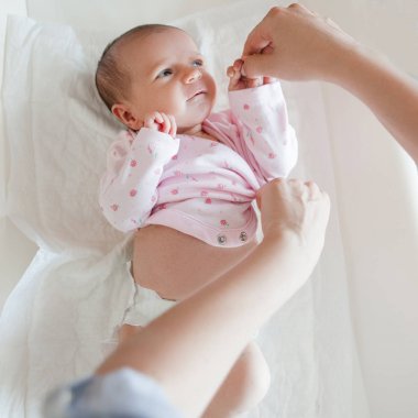 Anne, dikkatli bir şekilde yeni doğan bebeği Giydir