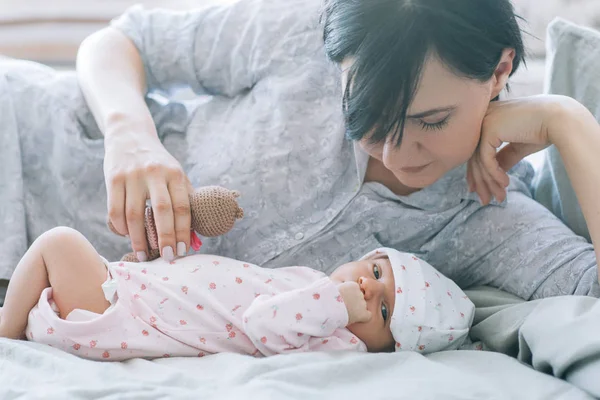 Moeder spelen met haar pasgeboren baby een teddy bear speelgoed — Stockfoto